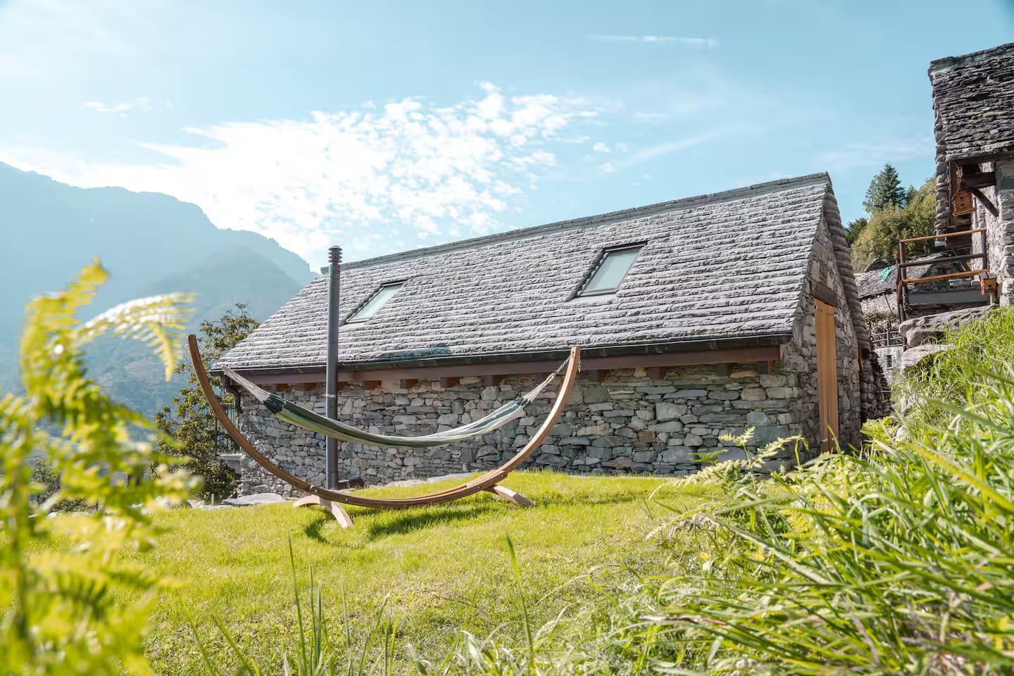 Rustico La Pezza seen from the meadow, with hammock and mountains